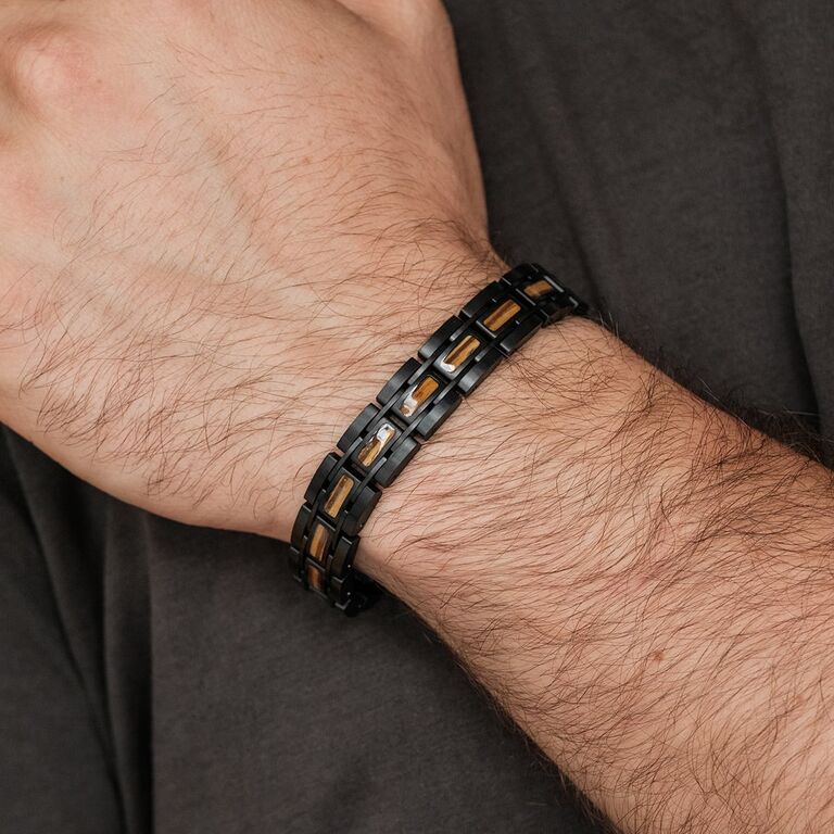 "Tremolo" armband med en elegant svart och guldfärgad kedjedesign på handleden.